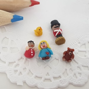 May include: Five miniature figurines made of polymer clay. The figurines include a red and white dressed doll, a blue and red dressed doll, a yellow chick, a brown teddy bear, and a red and white dressed soldier figurine.