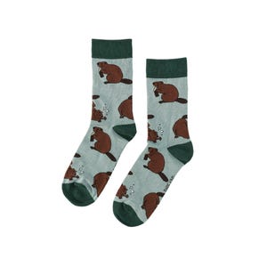 Könnte beinhalten: Ein Paar Socken mit einem hellblauen Hintergrund und einem sich wiederholenden Muster aus braunen Bibern, die Getränke halten. Die Socken haben dunkelgrüne Fersen und Zehen sowie dunkelgrüne Bündchen.
