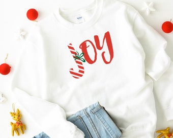 May include: White Christmas sweatshirt with a red and white candy cane graphic and the word "JOY" in red lettering.