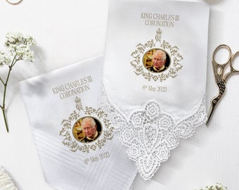 May include: Two white handkerchiefs with lace trim, featuring a gold embroidered design of a crown and floral motifs. Each handkerchief has a photo of King Charles III and the text "King Charles III Coronation 6th May 2023".