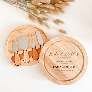 May include: A wooden cheese board with a set of four cheese knives and a personalized message that reads "Kate & Arthur Congratulations on your Engagement! Love from Mum and Dad xx".