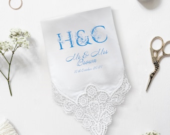 Può includere: Fazzoletto bianco con un delicato bordo in pizzo. Il fazzoletto presenta scritte floreali blu con le iniziali "H&C", e i nomi "Mr & Mrs Brown" con la data "10 ottobre 2021". Un articolo a tema matrimonio.