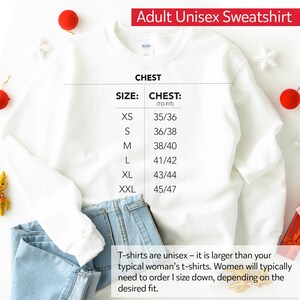 Op de afbeelding: Wit unisex sweatshirt met een maattabel die de borstmaten in inches aangeeft. De tabel toont maten XS tot en met XXL met overeenkomstige borstmaten van 35/36 tot 45/47 inch.