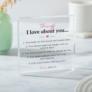 May include: A clear acrylic block with the text "things I love about you..." in pink script. The block lists five reasons, including making the recipient feel loved and making ordinary days special. Signed "love, Oliver X".