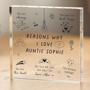 May include: A clear acrylic block with the text "Reasons why I love Auntie Sophie" and several illustrations including a bird, a lightbulb, a rainbow, a flower, a teddy bear, a star, a heart, and a speech bubble. The text "You are always so kind", "You give the best hugs", "You are the best", "You love me just the way I am love alfie x", and "You always support me" are also included.