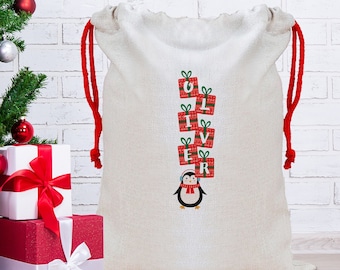 May include: A white canvas Santa sack with red drawstrings. The sack has a penguin design with a stack of presents that spell out the name "Oliver".