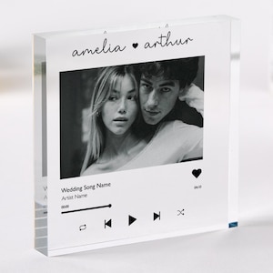 May include: A clear acrylic block featuring a black and white photo of a couple. The names "amelia ♥ arthur" are printed above the photo. Below the photo is a music player interface with song and artist name.