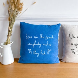 Può includere: Due cuscini decorativi, uno blu e uno beige, con testo bianco che dice "You are the friend everybody wishes they had".
