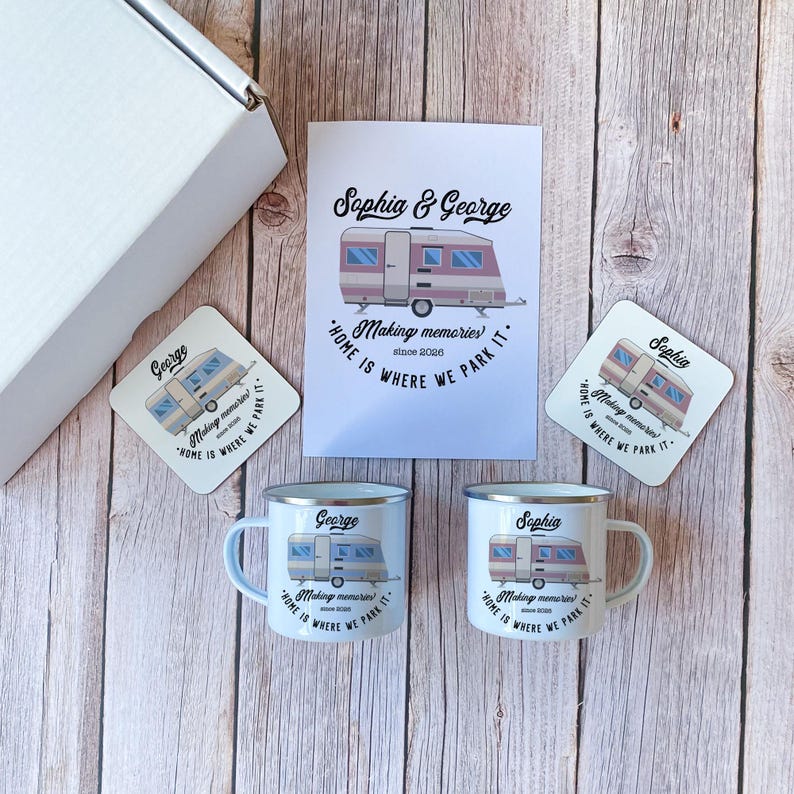 May include: A gift set featuring a white box, two white enamel mugs, two coasters, and a card, all with a caravan design. The mugs and coasters are personalized with names and the phrase "Home is where we park it."