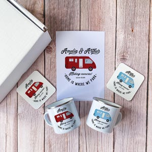 May include: A gift set featuring a red camper van design. The set includes two white enamel mugs, two coasters, and a card. The text on the items reads "Amelia & Arthur" and "Home is where we park."