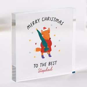 May include: A clear acrylic block with a Christmas-themed illustration. The image features a cartoon fox in a red coat and Santa hat holding a green Christmas tree. Text reads "MERRY CHRISTMAS TO THE BEST Stepdad."