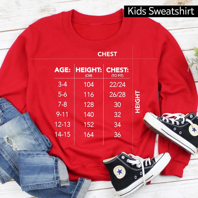 Op de afbeelding: Rood kindertrui met een maattabel op de voorkant. De tabel toont leeftijd, lengte in centimeters en borstomvang in inches. De tabel is getiteld "Kids Sweatshirt".