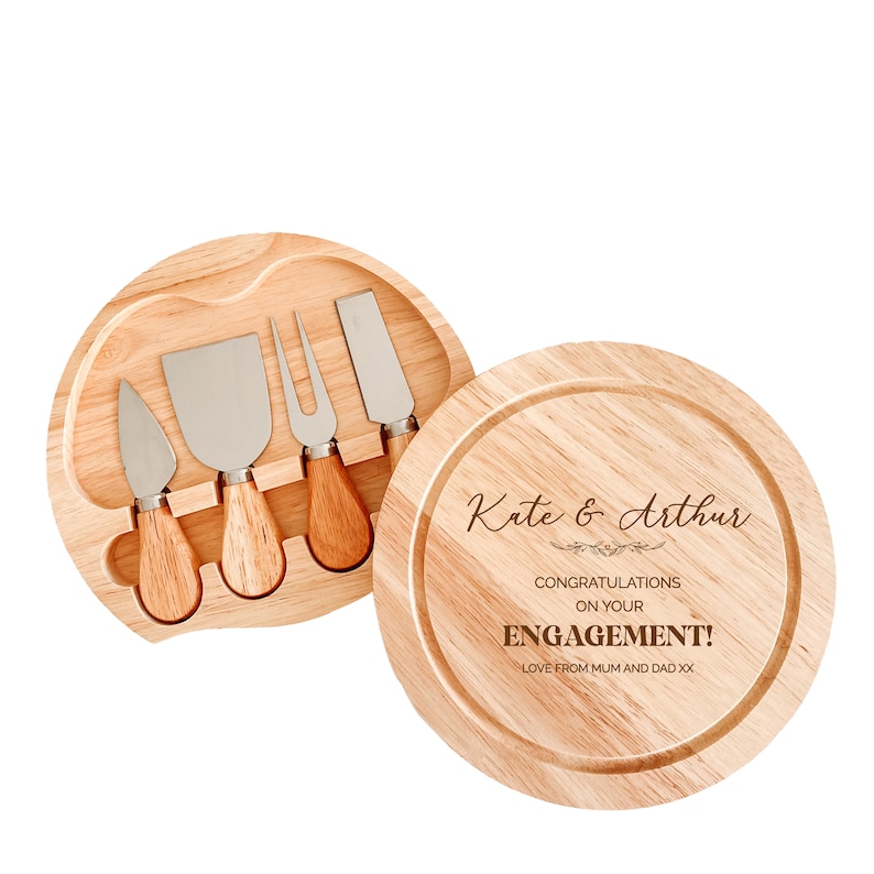 May include: A wooden cheese board with a set of four cheese knives and a personalized message that reads "Kate & Arthur Congratulations on your Engagement! Love from Mum and Dad xx".