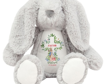 May include: A gray plush bunny with a white patch on its chest. The patch features a cross with green leaves and flowers, a small rabbit illustration, and the text "JACOB Baptized 17.04.2025".