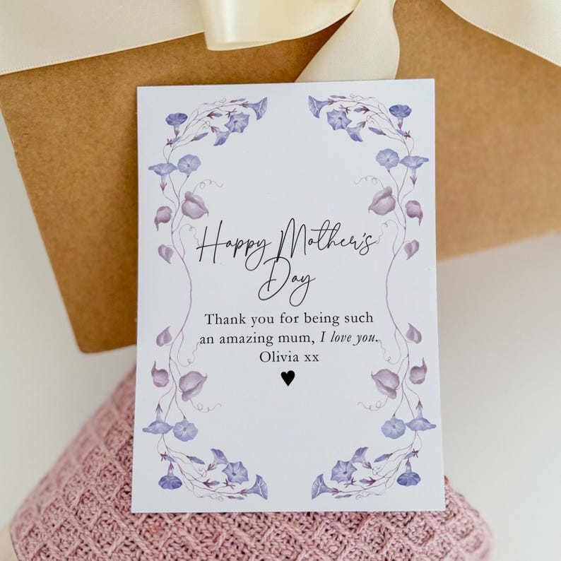May include: A white card with a purple floral border and the text "Happy Mother's Day" in black script. The card also includes the text "Thank you for being such an amazing mum, I love you. Olivia xx" in black.