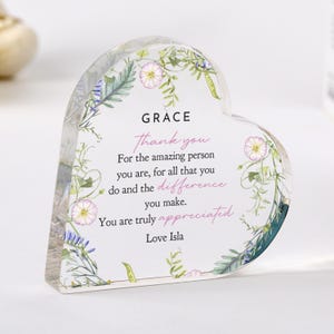 May include: A heart-shaped acrylic ornament with floral detailing and the words "GRACE Thank you" in black and pink script. The message continues with appreciation, signed "Love Isla."