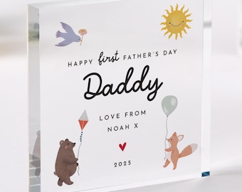 Puede incluir: Un bloque acrílico transparente con las palabras "Happy First Father's Day Daddy" y dibujos de un sol, un pájaro, un oso, un zorro, una cometa, un globo y un corazón. El bloque también incluye "Love from Noah X" y el año "2025".