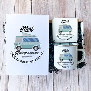 May include: A gift set featuring a light blue camper van design with the name "Mark" and the phrase "Home is where we park it." The set includes a card, a coaster, and a mug. The text "Making memories since 2026" is also present.