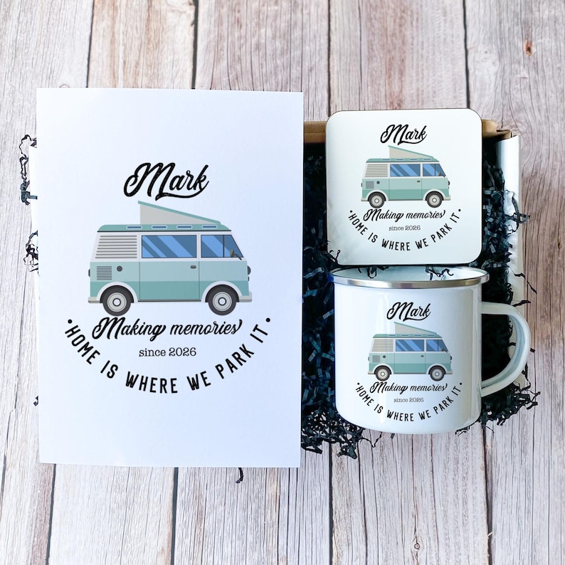 May include: A gift set featuring a light blue camper van design with the name "Mark" and the phrase "Home is where we park it." The set includes a card, a coaster, and a mug. The text "Making memories since 2026" is also present.