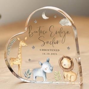 Op de afbeelding: Een hartvormig, transparant acryl-souvenir met een aquarel-illustratie van een giraffe, neushoorn en leeuw. De tekst "Beatrice Evelyn Sinclair" en "Christened 14.10.2025" is op het souvenir gedrukt.