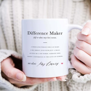 Può includere: Una tazza in ceramica bianca con un designo in bianco e nero che recita "Difference Maker (dif-er-uhns mey-ker) nome. Una persona dedicata che può avere un grande impatto, anche con solo una piccola azione o poche parole, qualcuno che fa la differenza nella vita degli altri. vedi anche: Sig.ra Baviy"