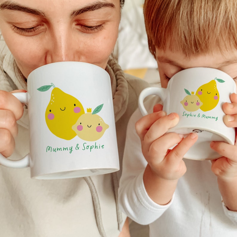 May include: Two white ceramic mugs with lemon illustrations and personalized text. The larger mug says "Mummy & Sophie" and the smaller mug says "Sophie & Mummy".