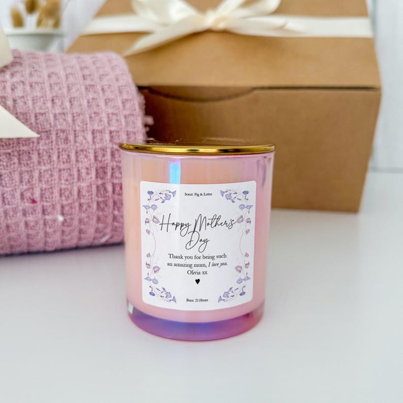 May include: A pink iridescent glass candle with a gold lid and a white label that says "Happy Mother's Day". The label also includes a floral design and the text "Thank you for being such an amazing mum, I love you. Olivia xx".