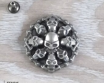May include: A silver metal skull charm with a chain design. The charm features a central skull surrounded by eight smaller skulls.