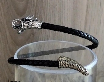 May include: Black leather bracelet with silver dragon head and tail accents.  The bracelet is coiled around a clear glass cylinder.  FENRIS WWW.FENRIS.WORLD