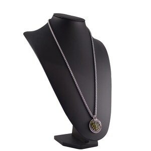 May include: A silver chain necklace with a round pendant featuring a green stone surrounded by silver filigree.