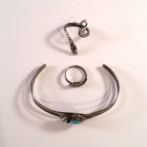 May include: Three silver rings, one with a turquoise stone, one with a snake design, and one plain band.