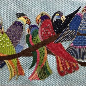 May include: A colourful needlepoint embroidery of five parrots perched on a branch. The parrots are a variety of colours, including green, red, blue, purple, and yellow. The background is a light blue.