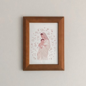 May include: A framed illustration of a woman holding a baby in her arms. The woman is wearing a white dress and a veil. The baby is wrapped in a white blanket. The illustration is surrounded by a circle of delicate flowers.