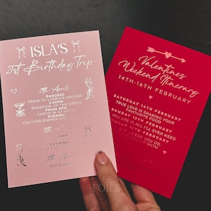 May include: Two invitation cards, one pink and one red, with silver text. The pink card reads "Isla's 21st Birthday Trip" with an itinerary. The red card says "Valentines Weekend Itinerary" with dates and text.