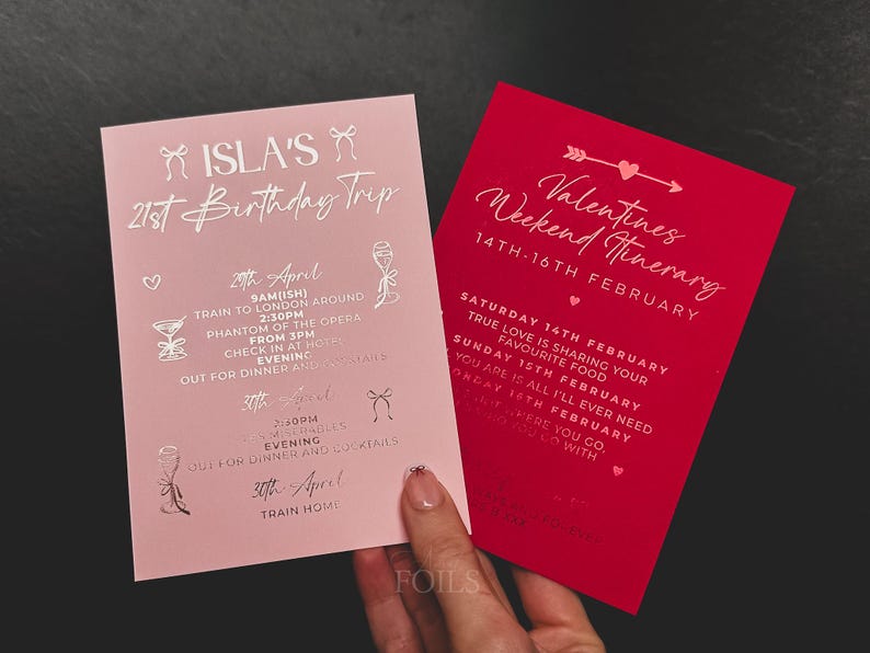 May include: Two invitation cards, one pink and one red, with silver text. The pink card reads "Isla's 21st Birthday Trip" with an itinerary. The red card says "Valentines Weekend Itinerary" with dates and text.