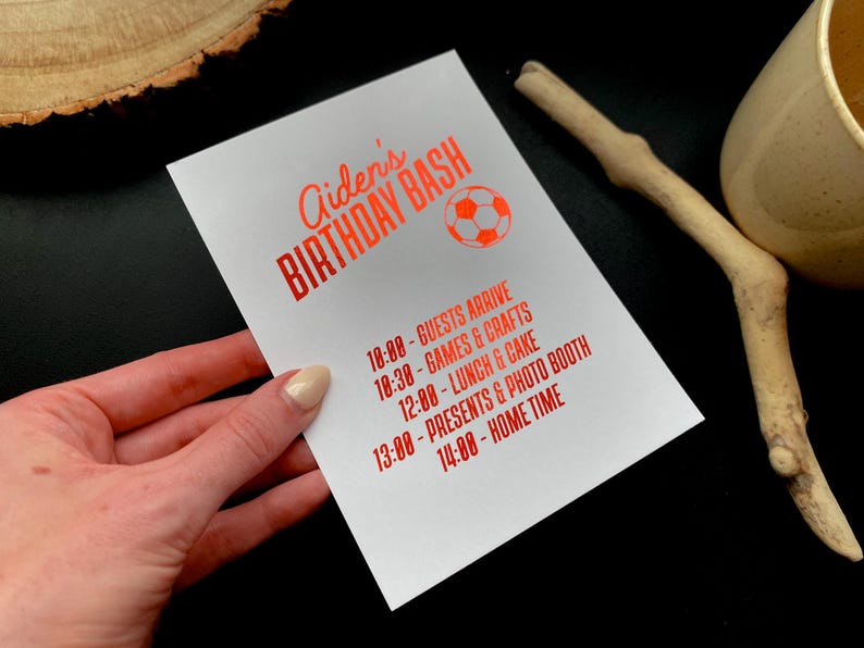 May include: White invitation card with red text that reads "Aiden's BIRTHDAY BASH" and a soccer ball graphic. The card lists the party schedule: Guests arrive at 10:00, Games & Crafts at 10:30, Lunch & Cake at 12:00, Presents & Photo Booth at 13:00, and Home Time at 14:00.