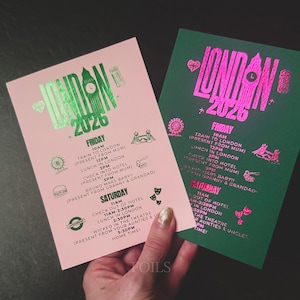 May include: Two event itinerary cards, one pink and one green, with metallic foil text. The cards read "London 2026" and list activities for Friday and Saturday, including train travel, lunch, and theater.