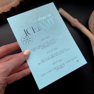 May include: A light blue travel itinerary titled "three days in Iceland." The itinerary includes a compass graphic and details for each day, such as visiting the Golden Circle and whale watching. The text is in a dark blue color.
