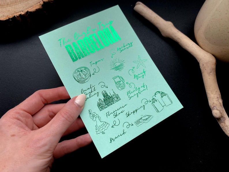 May include: A mint green card with the words "The Exclusive Tour BARCELONA" in shiny green lettering. The card features hand-drawn illustrations of tapas, a sunset, and other Barcelona activities.