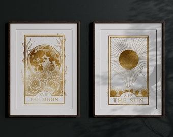 Könnte beinhalten: Zwei gerahmte Drucke von Tarotkarten, Der Mond und Die Sonne, mit goldenen Folienakzenten auf weißem Hintergrund.