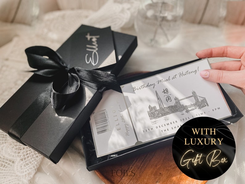 May include: A black gift box with a black ribbon and a white card inside. The card has a silver design of the London skyline and the text "Birthday Meal at Hutong!" The box is labeled "With Luxury Gift Box".