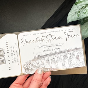 May include: A gold and white wedding invitation in the shape of a train ticket. The invitation reads "Join us as we celebrate our wedding day aboard the Jacobite Steam Train" and includes the date, time, and location of the wedding. The invitation also features a black and white illustration of a train.