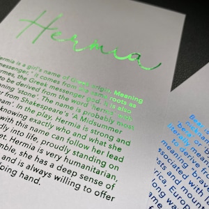 May include: Two white cards with text. The card on the left has the name "Hermia" in bright green foil, with a description of the name's origin and meaning. The card on the right has the name "Bear" in blue foil, with a description of the name's origin and meaning.