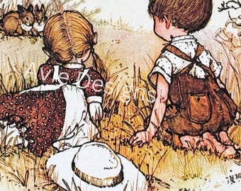 May include: Two children, a girl wearing a brown dress and a boy wearing overalls, are crouched down in a field of tall grass. The girl is wearing a white sun hat. They are looking at something off-camera.