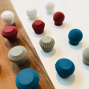 Peut inclure: Assortiment de boutons ronds et en forme de cupcake texturés et colorés, dans des couleurs variées, notamment rouge, bleu, gris et blanc.