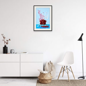 Op de afbeelding: Een ingelijste print van een stilleven met een rood koraalachtig object met roze en witte gedroogde bloemen op een blauwe achtergrond.
