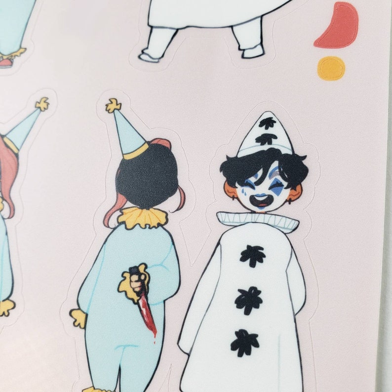 May include: Two cartoon clowns, one in a blue and white costume holding a bloody knife, the other in a white costume with black stars, smiling.
