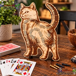 Peut inclure: Un plateau de cribbage en bois clair en forme de chat debout, avec des détails de fourrure gravés au laser en brun foncé et des trous pour marquer les points. Le jeu inclut deux piquets métalliques dorés et deux noirs pour le score.