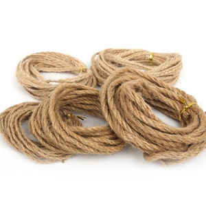 Può includere: Primo piano di diversi rotoli di spago marrone naturale, ognuno avvolto in un cerchio e legato con un filo dorato.