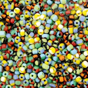 May include: A large assortment of colourful seed beads in various shades of blue, green, yellow, red, black, and white. The beads are small and round, and they are perfect for crafting jewellery or other projects.